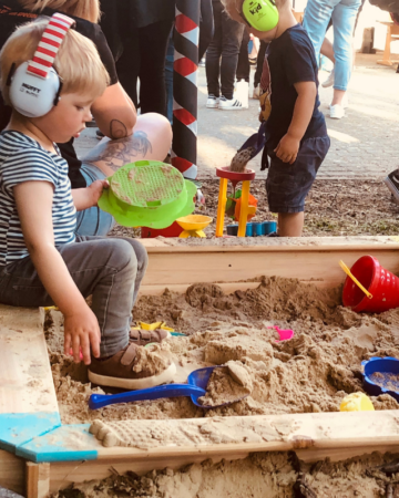 Kind mit Kopfhörer im Sandkasten auf Festival